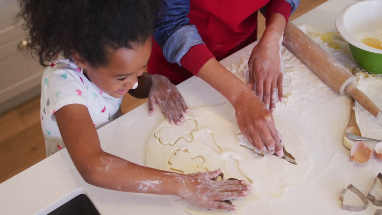 Happy african american mother and daughter using tablet and cooking together