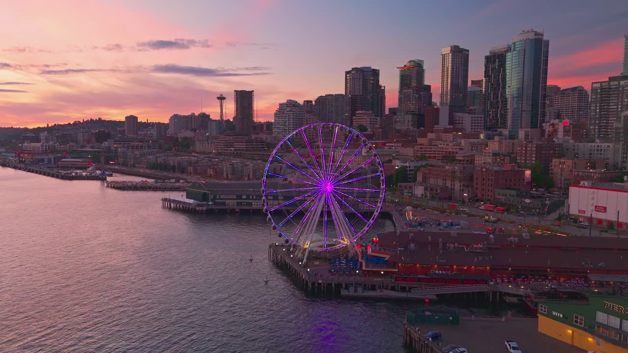 Seattle waterfront at sunset with the ferris wheel lighting up bright pink