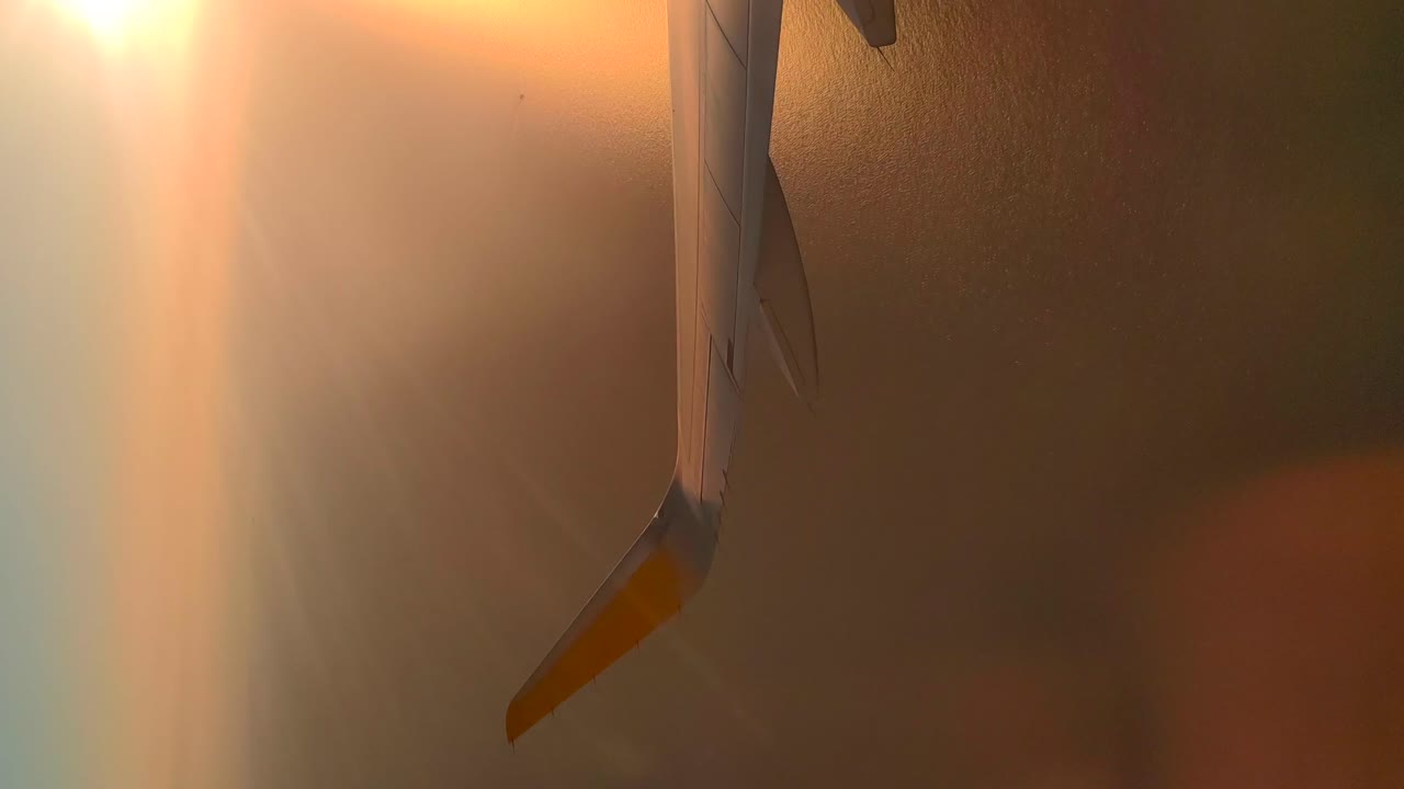 飛行機が海の上を飛行しているときの日没時の飛行機の翼の逆光