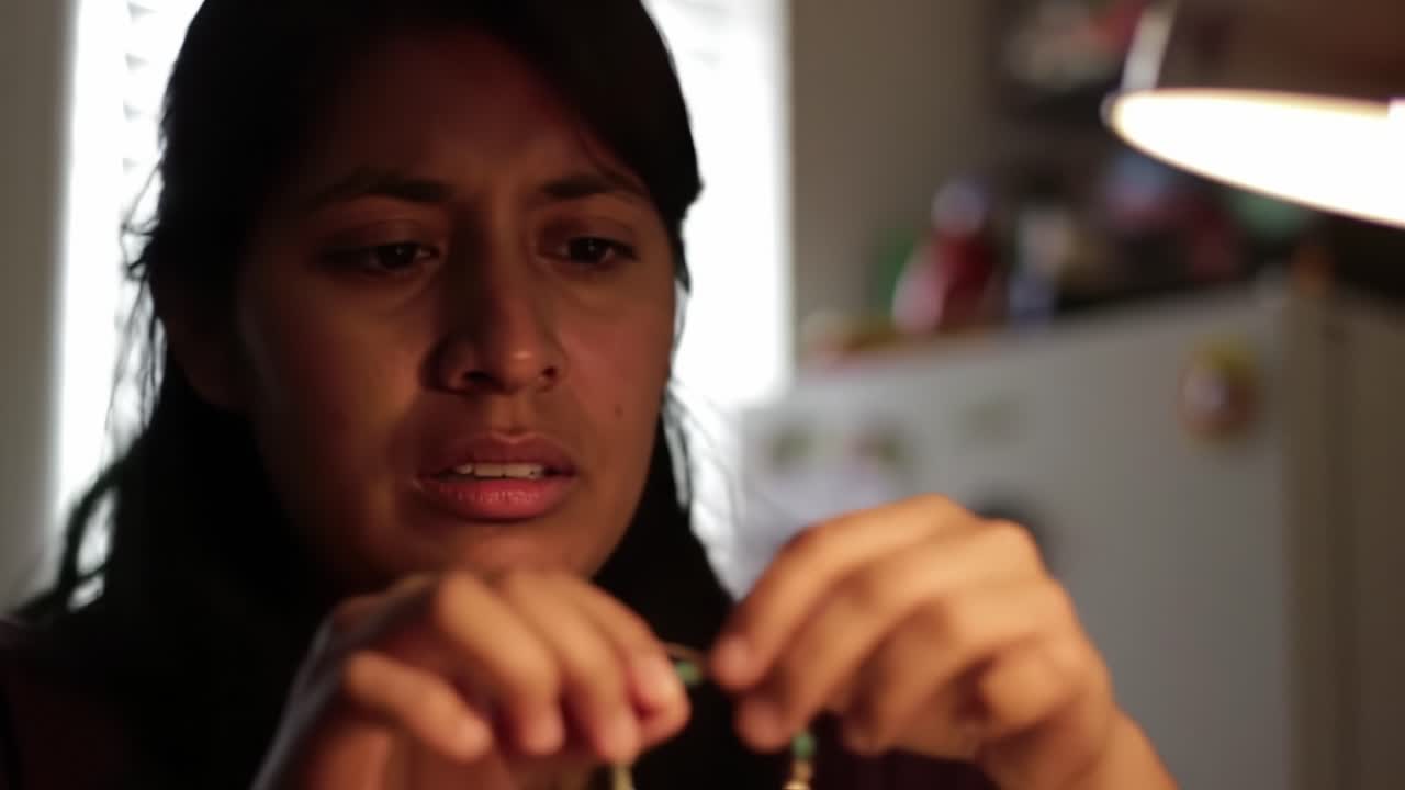 A Focused Individual Examines a Delicate Object Under Warm Light, Showcasing the Intricacies of Craftsmanship and Attention to Detail in a Personal Space