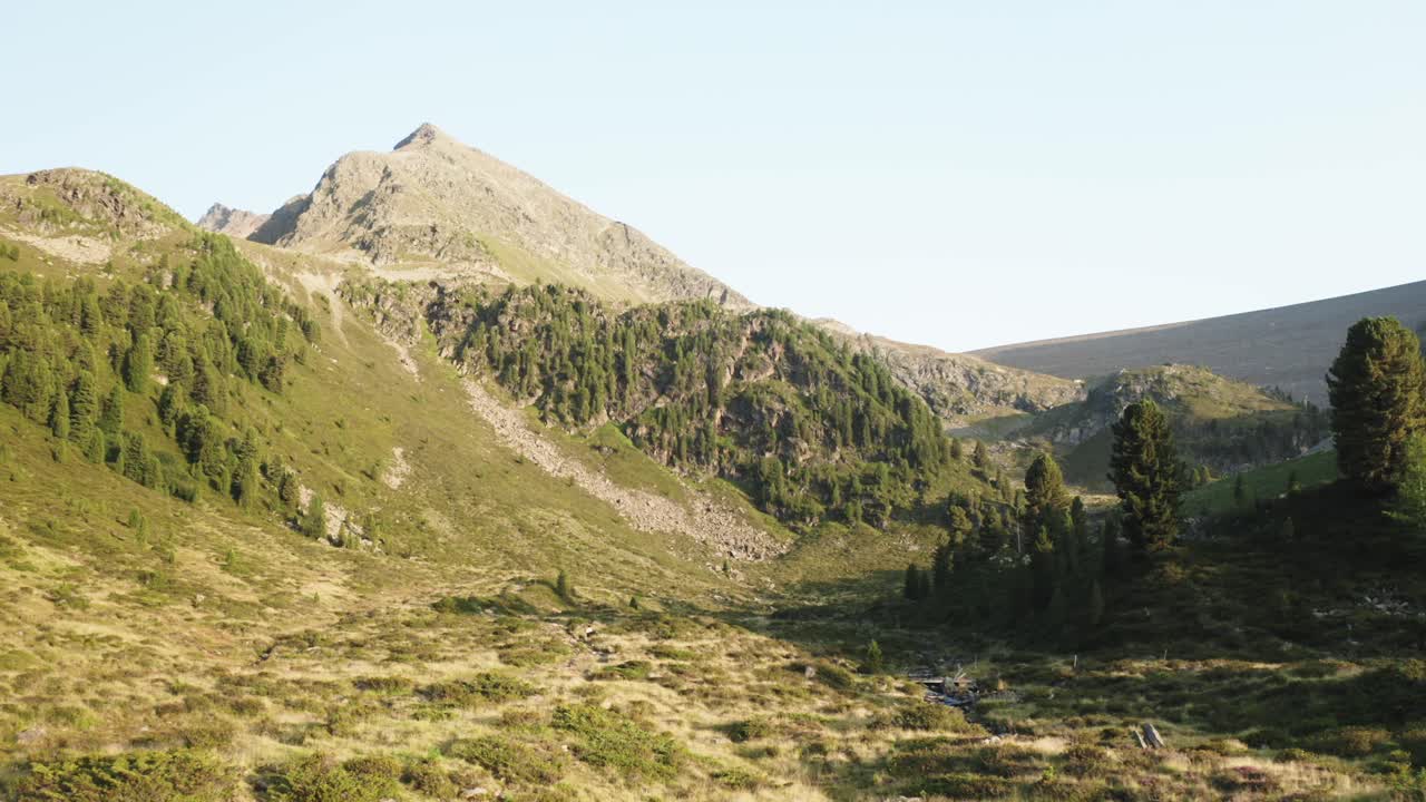 Sorvolo delle creste e delle valli alpine al tramonto a Kühtai, in Austria. Un'immagine calda e rilassante, perfetta per introduzioni, contenuti sulla natura o narrazioni cinematografiche.