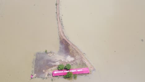 tin-shed school and surrounding land submerged by floodwater in bangladesh, aerial view