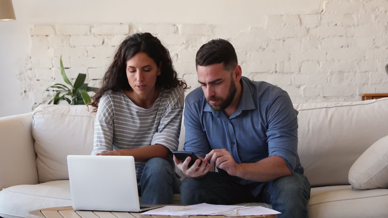 los cónyuges jóvenes comprueban los papeles financieros calculan los impuestos para pagar en línea