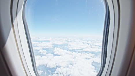 view from an airplane window showing a clear sky with fluffy clouds below