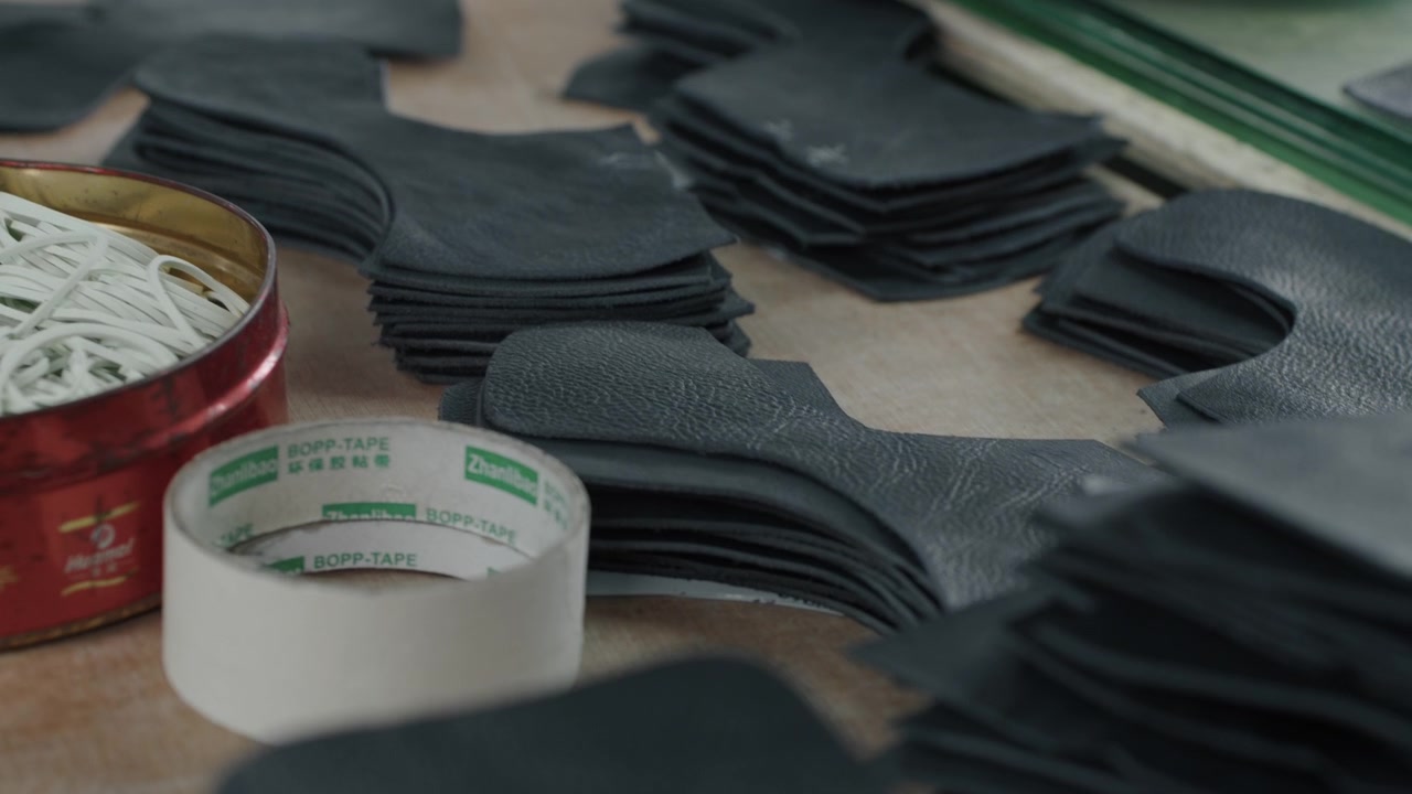 Stacks of cut leather shoe pieces arranged on a workbench in a factory setting