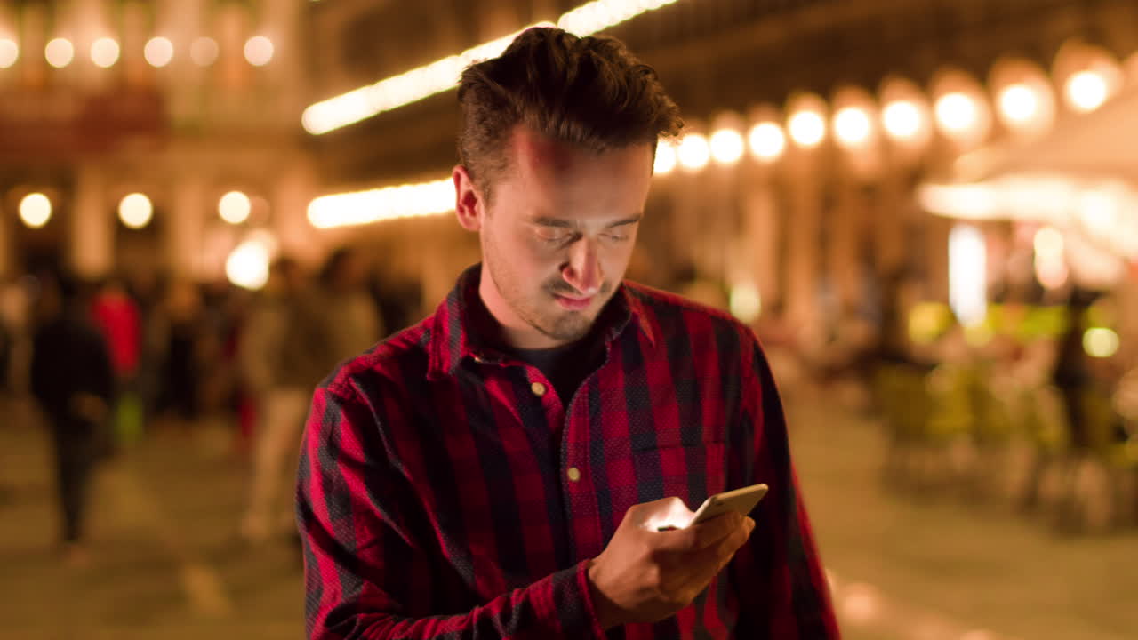 밤에 도시에서 스마트폰을 사용하는 남자