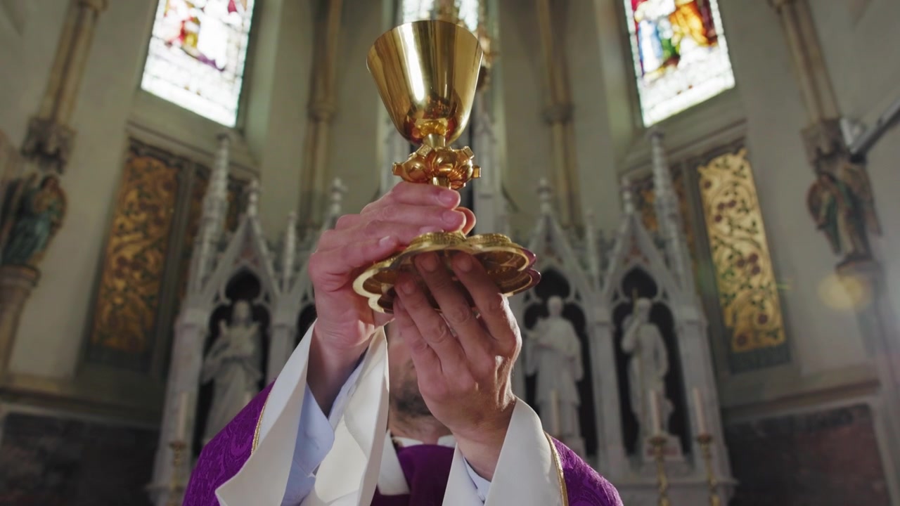 Sacerdote che innalza un calice d'oro sacro durante una cerimonia in chiesa, l'elevazione del calice durante il.
