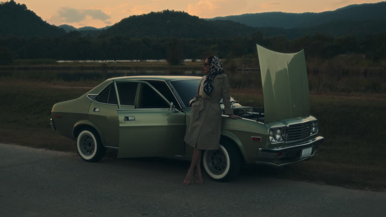 mujer por un coche de época al atardecer