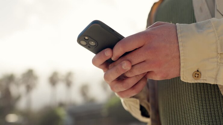 Telefono, mani e persona che digita all'aperto