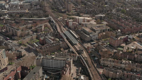 tomada aérea del tren del ferrocarril nacional de gran inglaterra que llega a la estación de hackney downs
