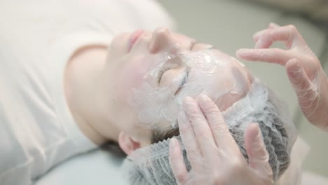 woman undergoing facial treatment at cosmetologist clinic