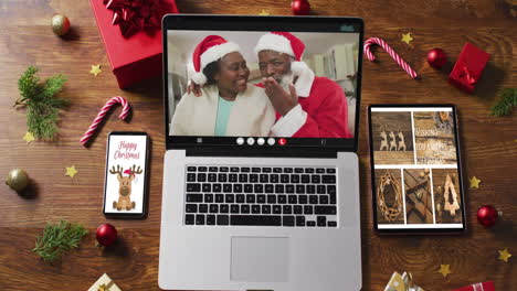 african american senior couple on video call on laptop, with smartphone, tablet and decorations