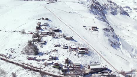 Aerial-orbit-establishing-European-style-mountain-cabins-in-the-snowy-village-of-Farellones-and-skiers-descending-Farellones-Park-Chile