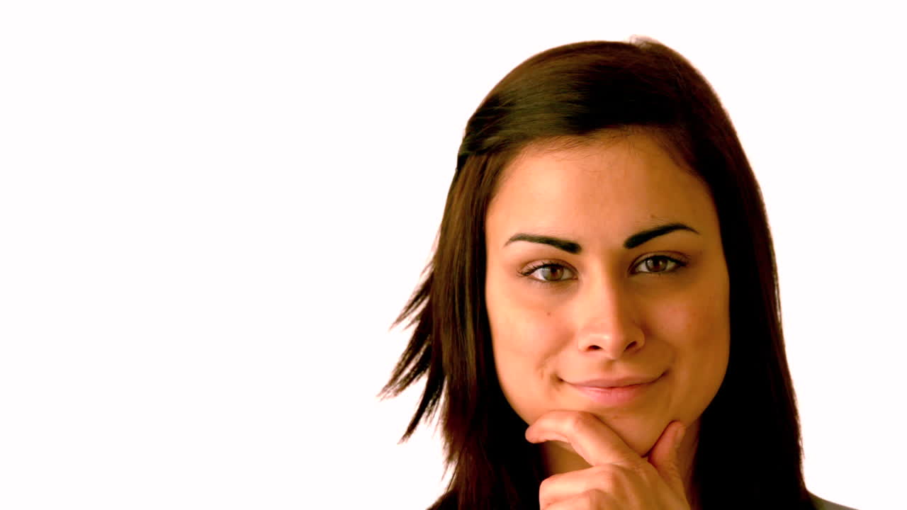 bonita morena sonriendo a la cámara con la mano en la barbilla