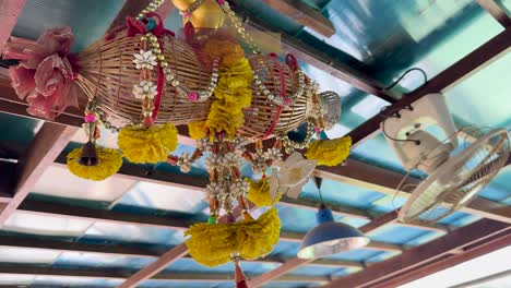 vibrant floral and fan decorations hang under a sunlit roof at a clifftop restaurant in phuket, thailand