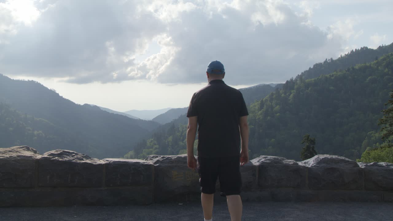 Uomo caucasico di mezza età che cammina verso un punto panoramico delle Great Smoky Mountains al rallentatore.