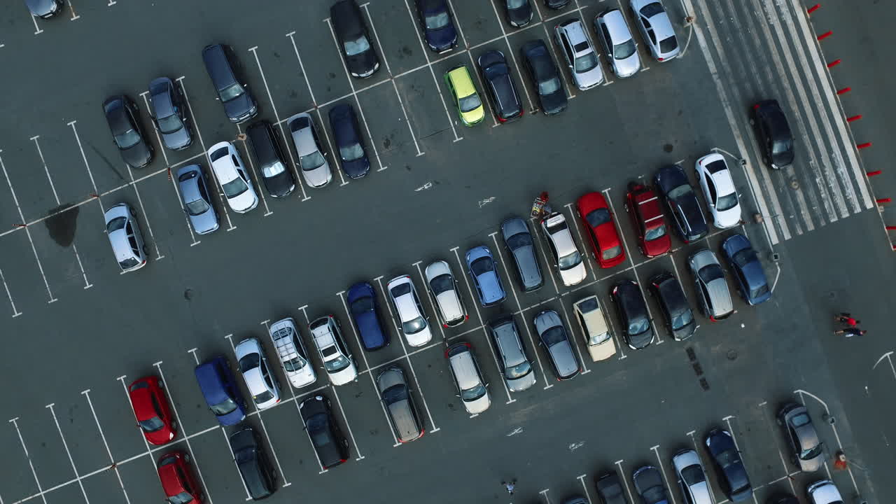 Drone filmer folk som går på parkeringsplass. Droneopptak av bil som kjører på parkeringsplass.