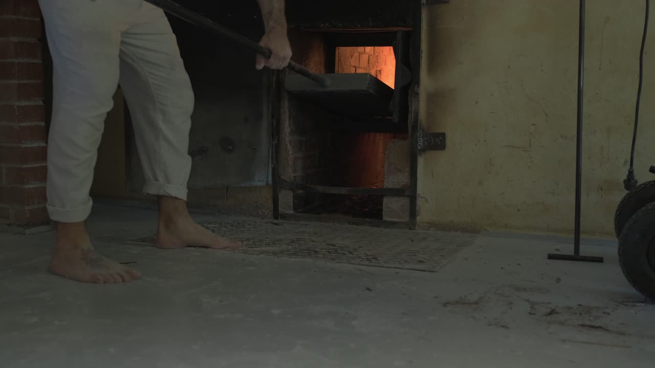 baker is take a big shovel, to take of the traditional stone oven, embers and fire