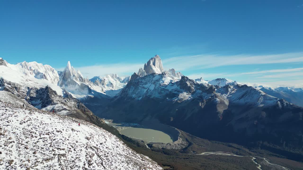 4K aerial of Laguna Torre with the iconic Fitz Roy and Cerro Torre in view. Clear skies reveal snowy summits and dramatic Patagonian landscapes