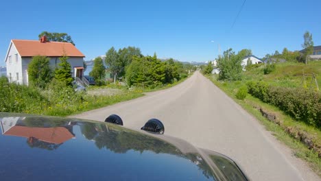 hood view driving car through norwegian village with narrow highway, northern norway, slow motion 60p