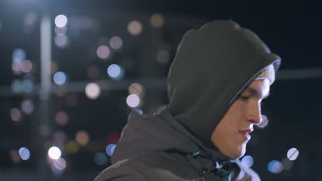 close-up of coach training at night while juggling football, illuminated by street lights, with bokeh light effect and residential buildings in the background