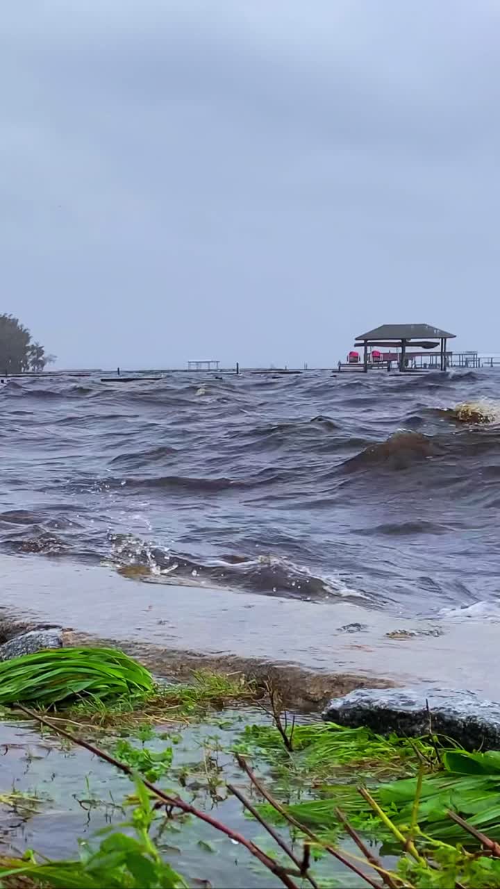 Ocean waves from hurricane flooding over bulkhead, destroyed pier and dock house
