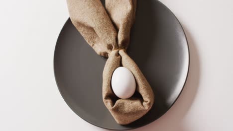 Egg-and-ribbon-in-shape-of-rabbit-on-plate-on-white-background