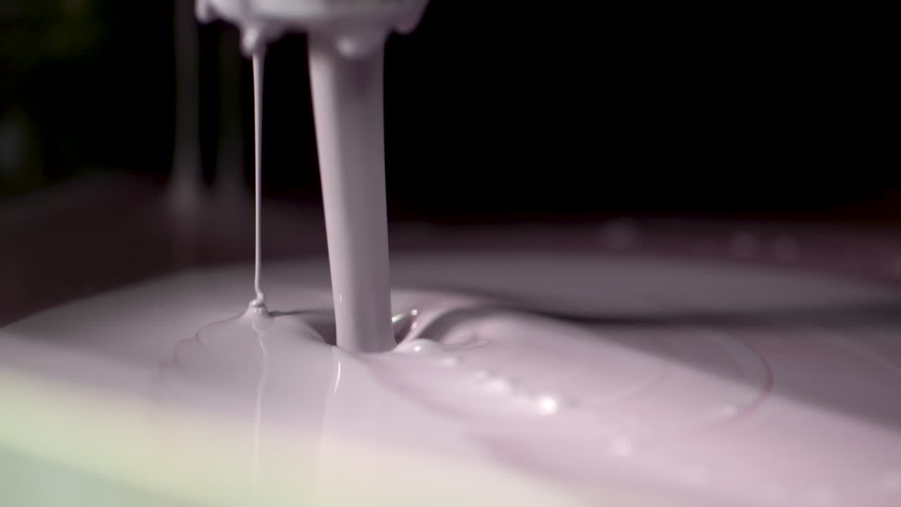Extreme closeup of pale violet paint endlessly pouring out of a valve