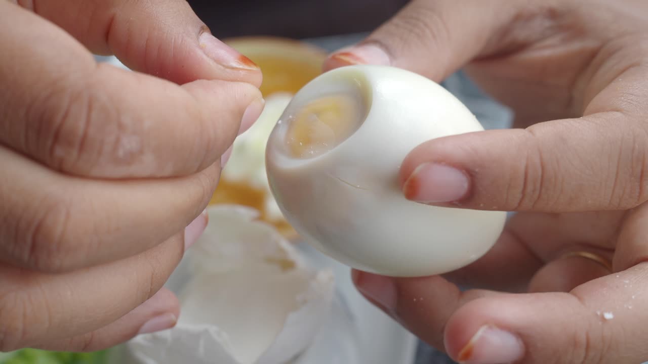 Hands peeling a hard-boiled egg