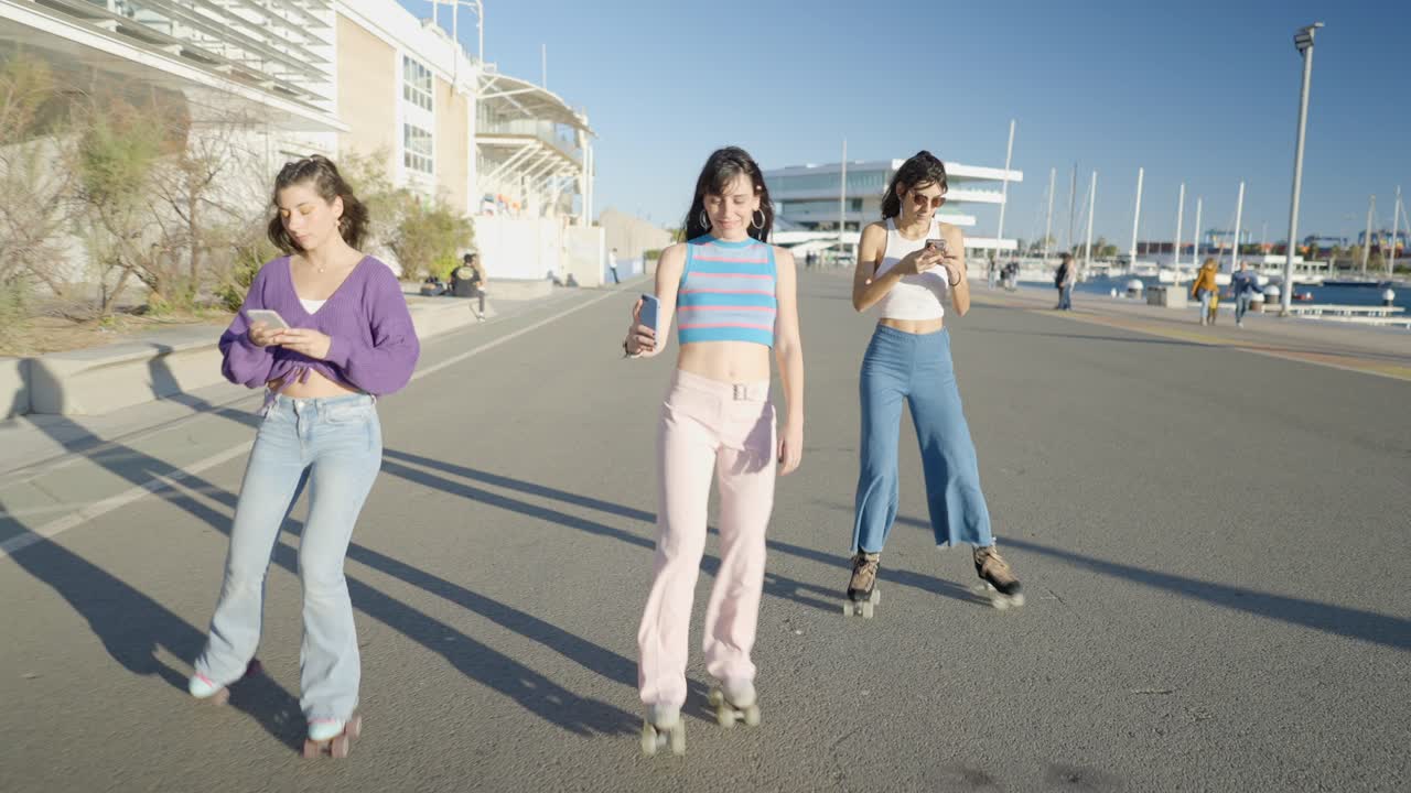 Three friends roller skating in the city, using mobile phones