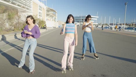 three friends roller skating in the city, using mobile phones