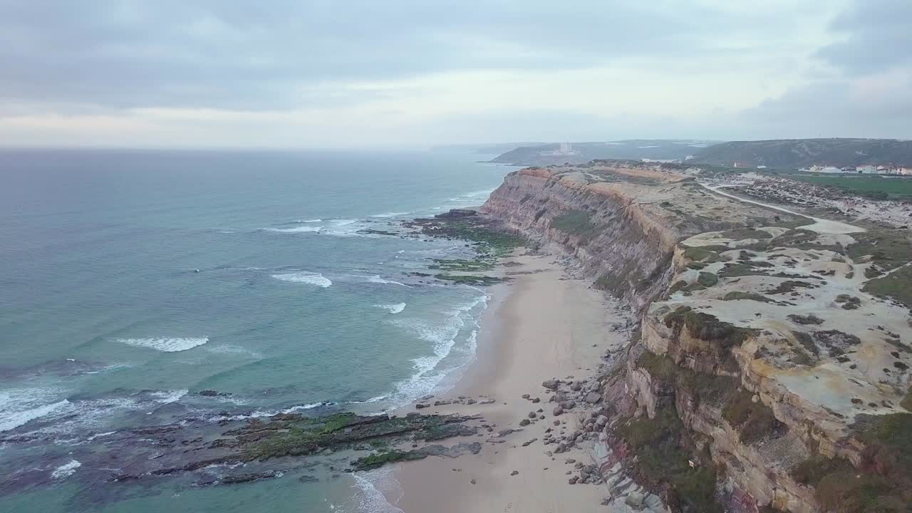 Panoramic scenery flying over a cliff drop to a small beach