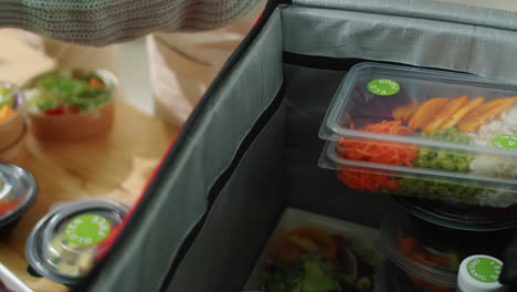 hands of woman in gloves packing containers with eco food for delivery