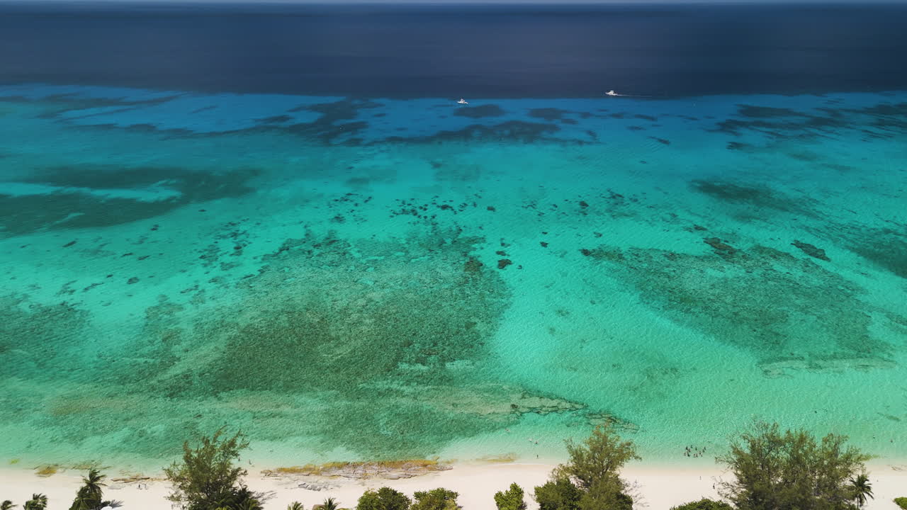 Drone ascends above Grand Cayman’s white sands and vivid blue Caribbean water
