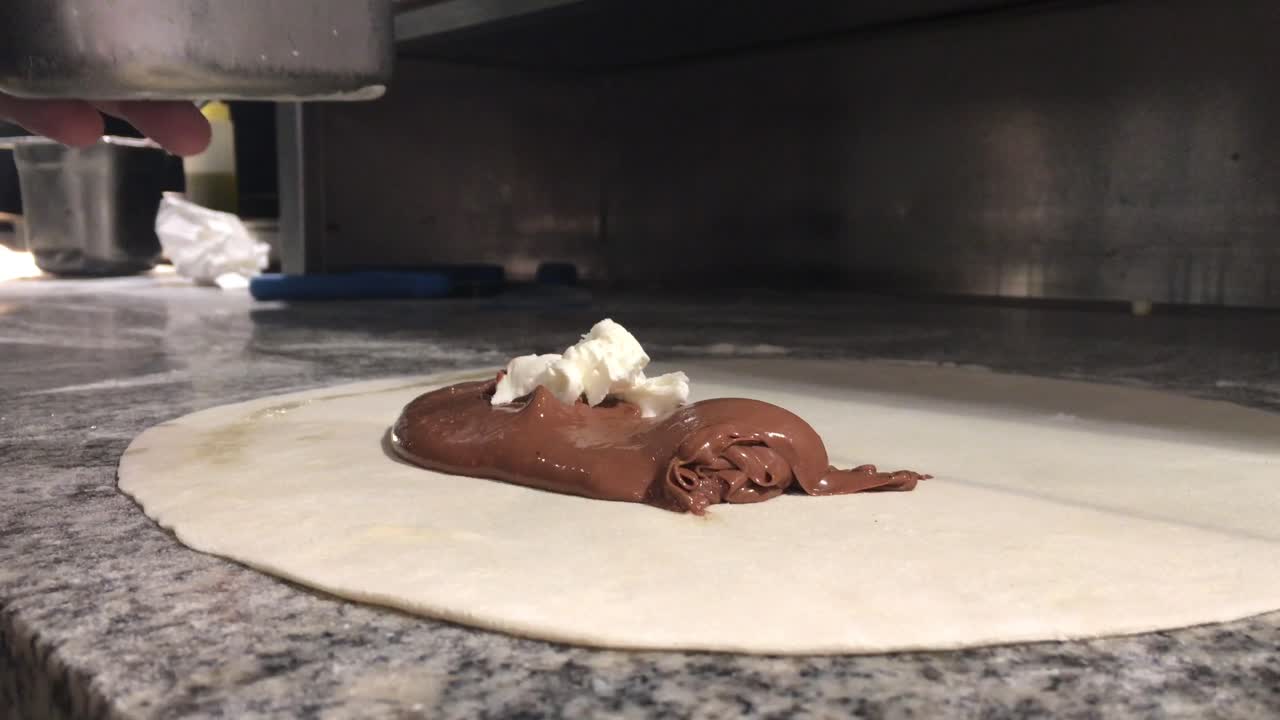 Cuoco prepara pasta dolce con pralina al cioccolato e crema al mascarpone.