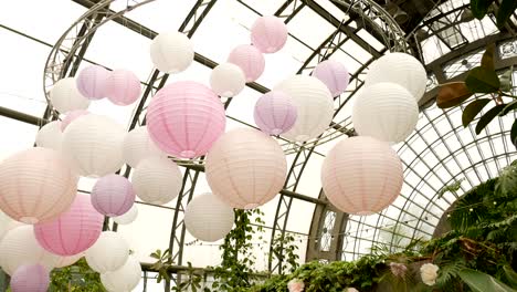 white pink balls of rice paper hanging on the branches of green trees