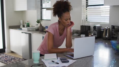 Mixed-race-woman-in-kitchen-using-laptop