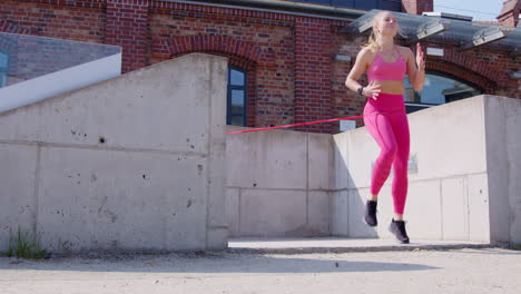 Slo-mo-of-young-blonde-woman-exercising-with-resistance-band-outdoors