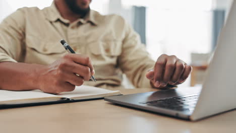 hands, laptop and a man writing in a notebook