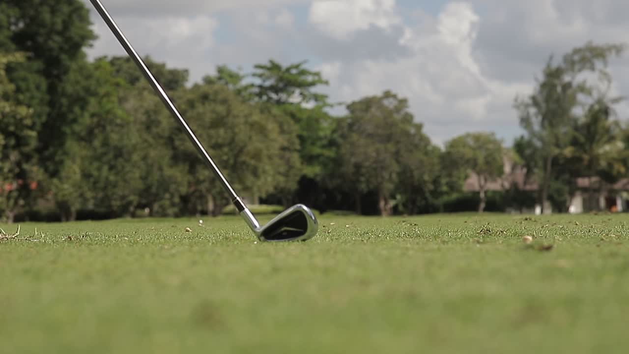 Inquadratura ravvicinata dal basso sul campo da golf, mentre si colpisce una pallina da golf attraverso il percorso, al rallentatore.