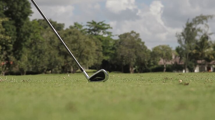 Inquadratura ravvicinata dal basso sul campo da golf, mentre si colpisce una pallina da golf attraverso il percorso, al rallentatore.
