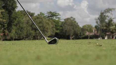 low angle close up shot at the golf club, hitting a golf ball across a golf course, slow motion