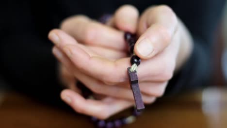 woman-praying-with-hands-together-with-cross-on-black-background-with-people-stock-video