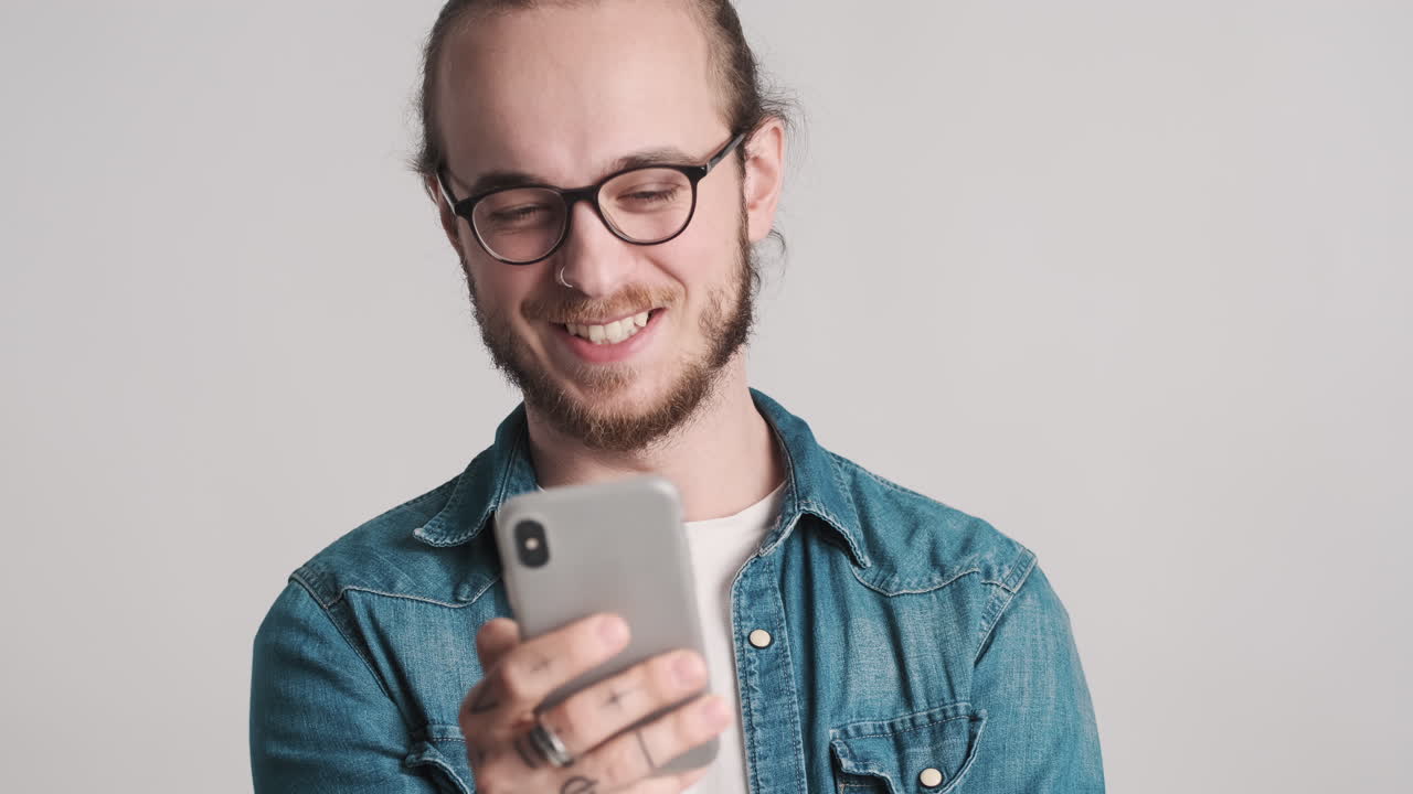 Caucasian young man using smartphone on camera.