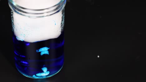 el hielo seco reacciona en líquido azul, creando humo.