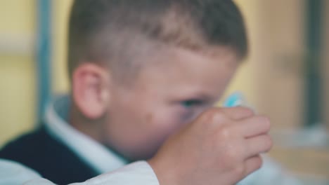 schoolboy-plays-with-spinner-putting-toy-on-nose-closeup