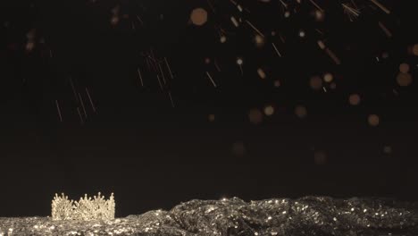 diamond pageant crown on a turning display with silver sequins and a black background with confetti particles