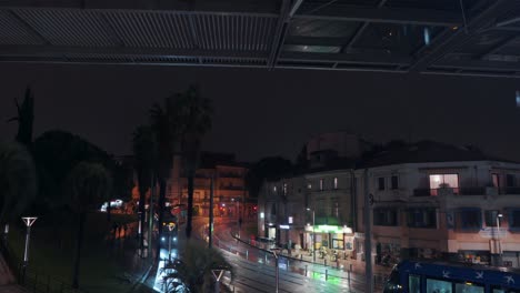 A-yellow-tram-is-coming-and-a-blue-tram-is-leaving-on-a-rainy-night,-Montpellier---France