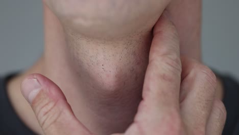 Close-up of a man&#039;s neck and throat with a finger touching the Adam&#039;s apple
