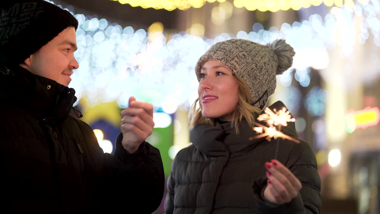 um casal a celebrar com o sparkler numa cidade à noite.
